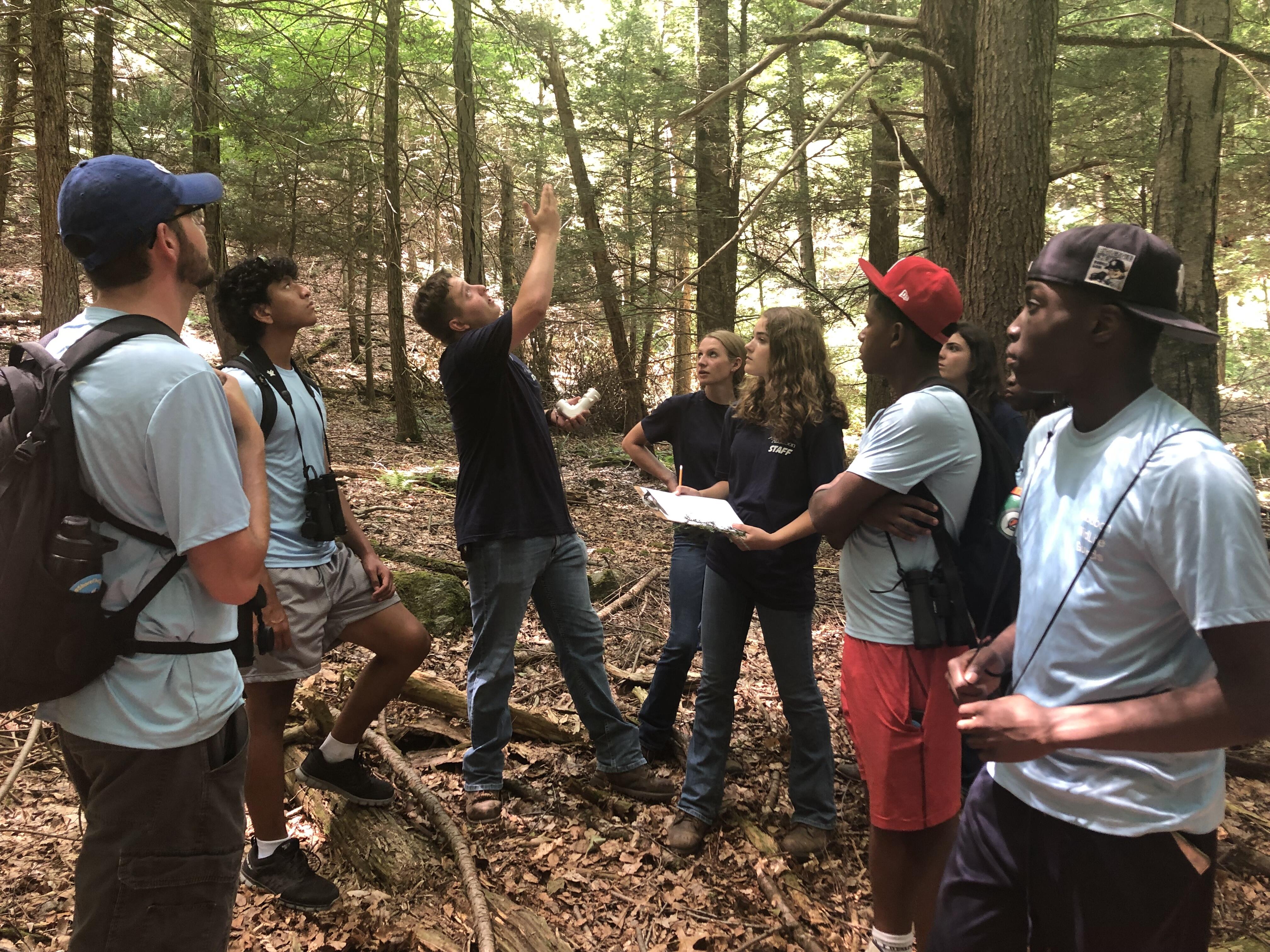 Several high school students watch a demonstration on forestry.